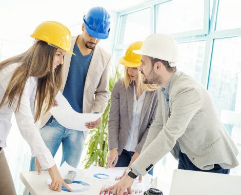 Image of four successful business partners working at meeting in office.Construction workers checking the architectural plans before they start the building project.
